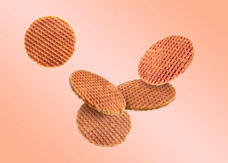 Yummy Dutch waffles (stroopwafels) flying on pink beige gradient backgroundの写真素材