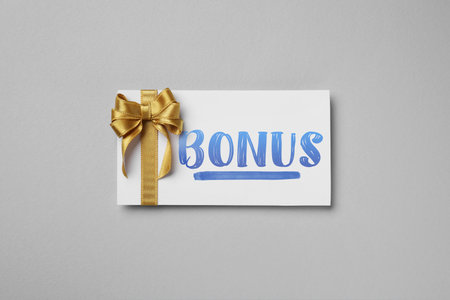 Bonus card with golden bow on grey background, top viewの写真素材