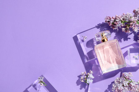 Flat lay composition with bottle of perfume and lilac flowers on violet background. Space for textの写真素材
