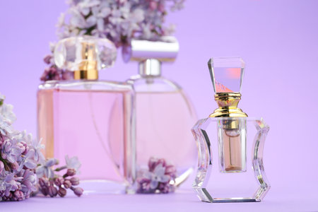 Bottles with perfumes and lilac flowers on violet background, selective focusの写真素材