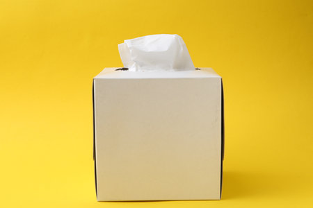 Box with paper handkerchiefs on yellow backgroundの写真素材
