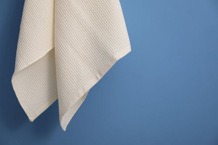 Clean waffle towel hanging on blue wall, closeup. Space for textの写真素材