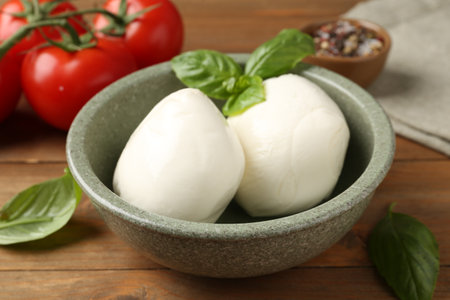 Tasty mozzarella balls, tomatoes and basil on wooden table, closeupの写真素材