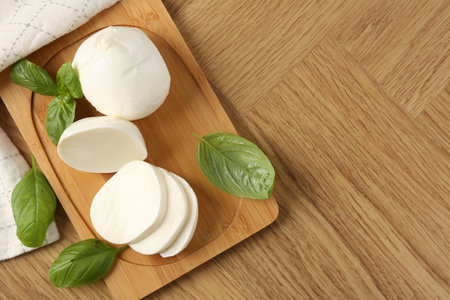 Tasty mozzarella and basil on wooden table, flat lay. Space for textの写真素材