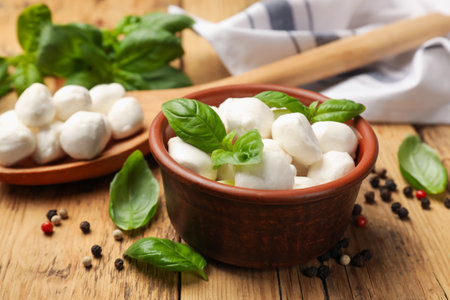 Mozzarella cheese balls with basil and peppercorns on wooden table, closeupの写真素材