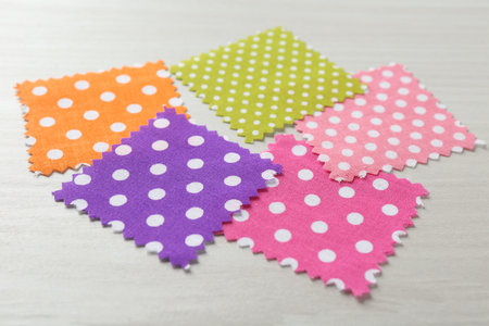 Samples of different fabrics on white wooden table, closeup