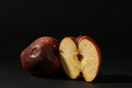 Damaged red apples on black background. Space for text