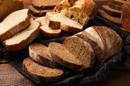 Different types of fresh bread on wooden table, closeup
