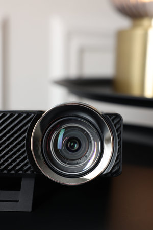 Modern video projector on black table indoors, closeup