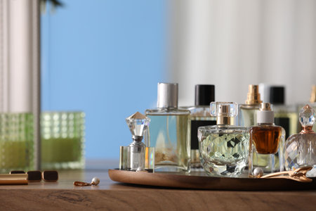 Bottles of different perfumes and accessories on wooden table, closeup. Space for textの写真素材
