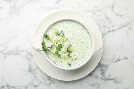 Tasty cucumber soup with dill and microgreens on white marble table, top viewの写真素材