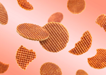 Yummy Dutch waffles (stroopwafels) flying on pink beige gradient background