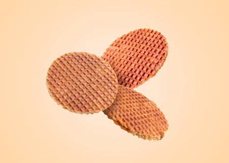 Yummy Dutch waffles (stroopwafels) flying on beige backgroundの写真素材