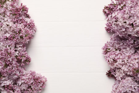 Beautiful lilac flowers on white wooden table, flat lay. Space for text