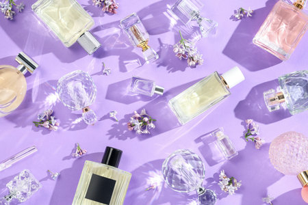 Flat lay composition with perfume bottles and lilac flowers on violet backgroundの写真素材