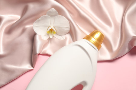Bottle of fabric softener, orchid flower and beige cloth on pink background, above viewの写真素材