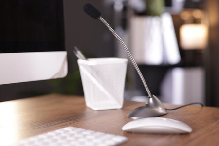 Microphone and computer on wooden desk indoorsの写真素材