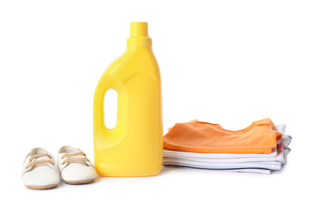 Bottle with fabric softener, shoes and baby clothes isolated on whiteの写真素材