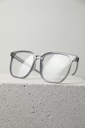 Stylish glasses on stone surface against light grey background, closeup