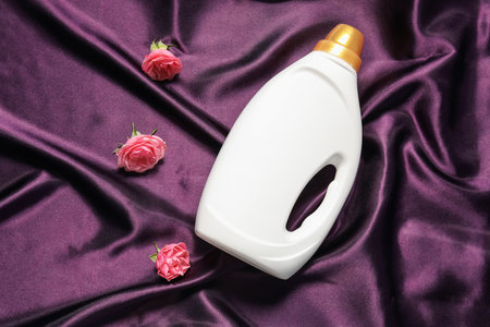 Bottle of fabric softener and flowers on purple cloth, flat layの写真素材