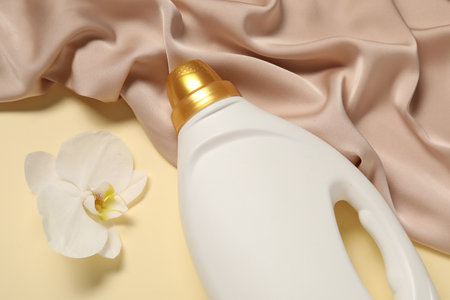 Bottle of fabric softener, orchid flower and color cloth on beige background, flat layの写真素材