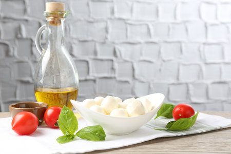 Tasty mozzarella cheese balls, tomatoes, basil and oil on wooden tableの写真素材