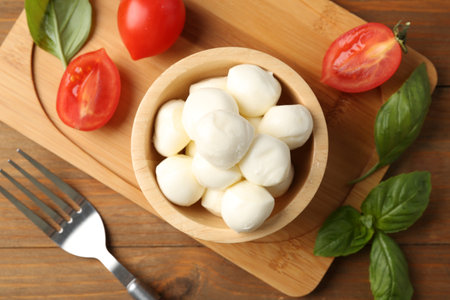 Tasty mozzarella balls, tomatoes and basil on wooden table, flat layの写真素材