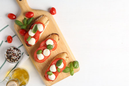 Tasty sandwiches with mozzarella cheese, tomatoes and basil on white table, flat lay. Space for textの写真素材