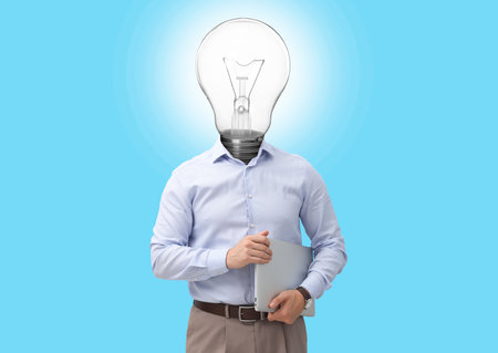 Man with glowing lightbulb instead of head and laptop on light blue backgroundの写真素材
