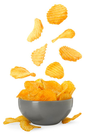 Tasty crispy potato chips falling into bowl on white backgroundの写真素材