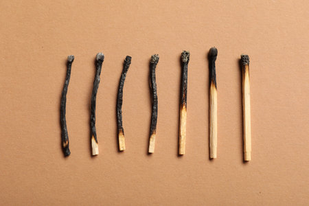 Burnt matches on beige background, flat layの写真素材