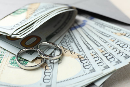 Two silver wedding rings, dollar banknotes and envelope on white table, closeupの写真素材