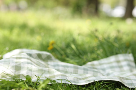 Checkered blanket for picnic on green grass outdoors, closeup