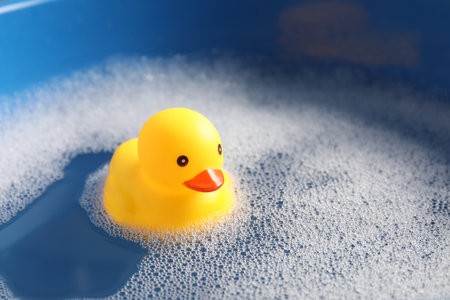 Cute rubber duck floating in water with bubbles, closeupの写真素材