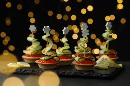 Tasty canapes on black table against dark background with blurred lights, closeup. Bokeh effectの写真素材