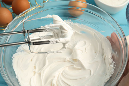 Whisking cream with hand mixer at table, closeupの写真素材