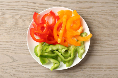 Slices of fresh colorful bell peppers on wooden table, top viewの写真素材
