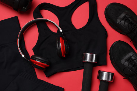 Sportswear, sneakers, dumbbells, headphones and water bottle on red background, flat layの写真素材