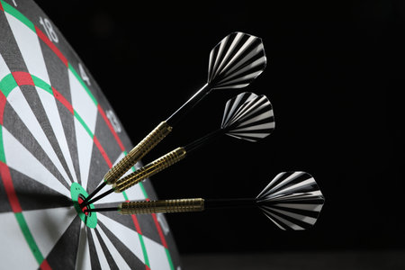 Targeting. Dart board with arrows on black background, closeup