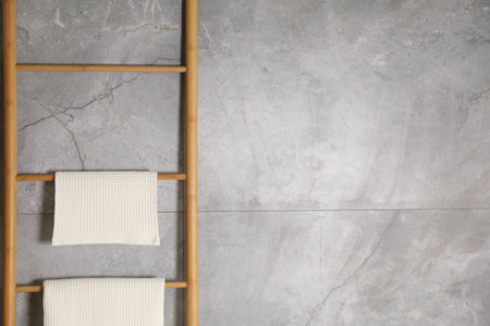 Clean waffle towels on wooden rack near grey wall. Space for textの写真素材