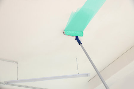 Painting white ceiling with turquoise dye indoors, low angle viewの写真素材