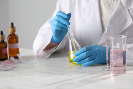 Professional perfumer developing luxury perfume at white wooden table in laboratory, closeupの写真素材