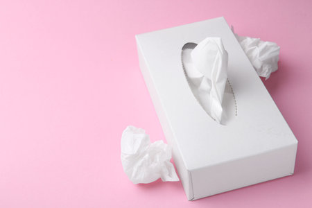 Box with paper handkerchiefs and crumpled tissues on pink background, closeup. Space for text