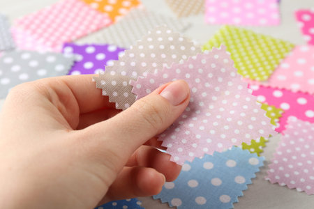 Woman with samples of different fabrics on white wooden table, closeup