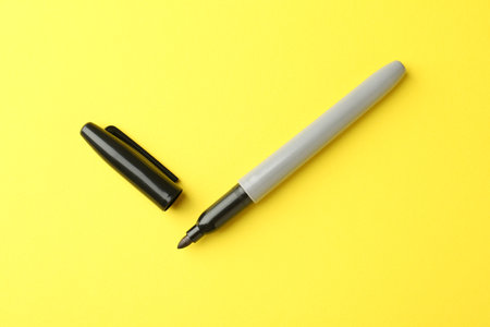 One black marker on yellow background, top viewの写真素材
