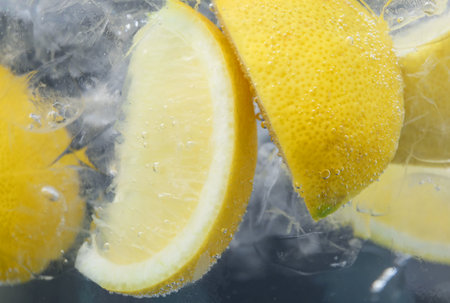Refreshing soda water with slices of lemon and ice in glass on dark background, closeupの写真素材