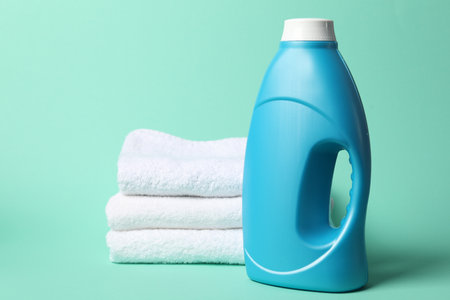 Bottle of fabric softener and towels on turquoise backgroundの写真素材