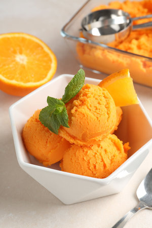 Tasty orange sorbet, fresh fruit, mint, spoon and scoop on light table, closeupの写真素材