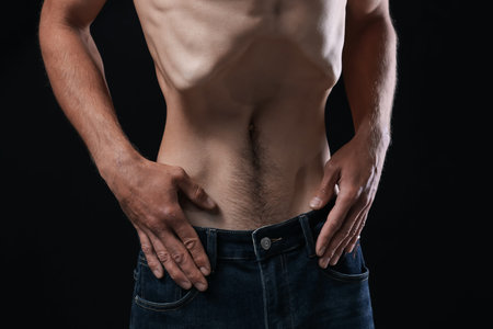 Man suffering from anorexia on black background, closeupのeditorial素材