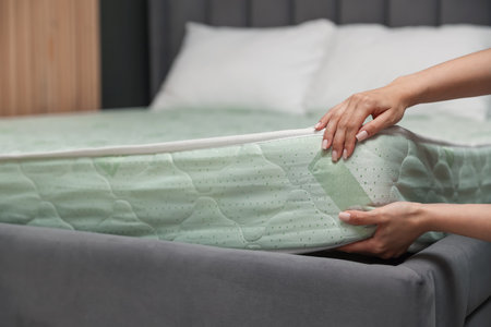Woman putting new soft mattress on bed indoors, closeupの写真素材